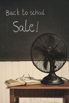 Vintage electric fan with book on table 