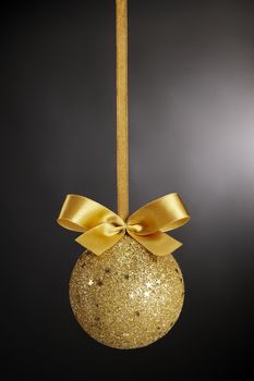 Gold Christmas ball with bow on black background