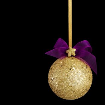 Gold Christmas ball with bow on black background. Black copy space for your text and logo.