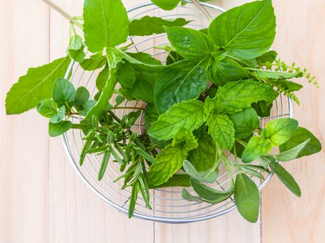 Fresh green herbs harvest from garden in the basket on wooden  background .