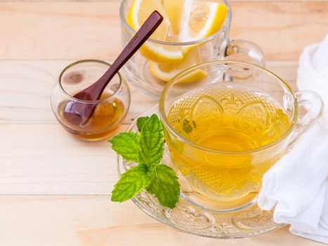 Cup of herbal tea with fresh green mint ,honey and lemon on wooden background.