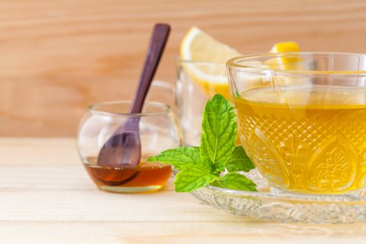 Cup of herbal tea with fresh green mint ,honey and lemon on wooden background.