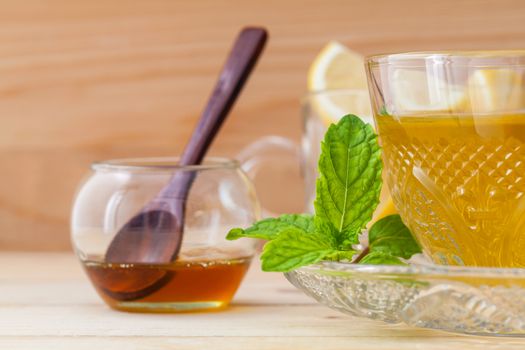 Cup of herbal tea with fresh green mint ,honey and lemon on wooden background.