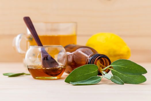 Cup of herbal tea with  fresh sage ,honey and lemon on wooden background.