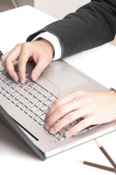 Asian man's hands typing on laptop keyboard