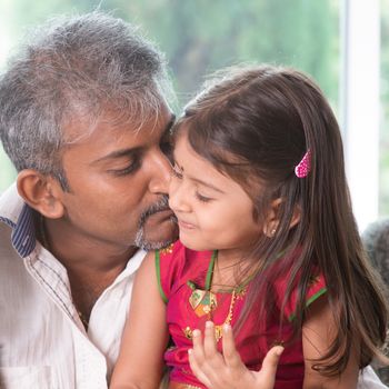 Happy Indian family at home. Asian dad kissing his toddler. Father and daughter indoor lifestyle.