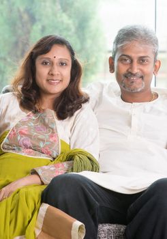 Indian couple. Portrait of mid age beautiful Indian family in traditional costume at home. Indian husband and wife indoor living lifestyle.