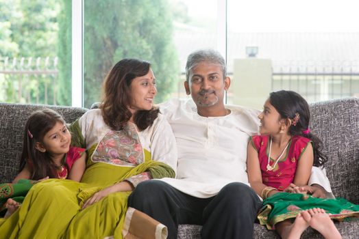 Happy Indian family at home. Asian parents bonding with their kids, sitting on sofa. Parents and children indoor lifestyle.
