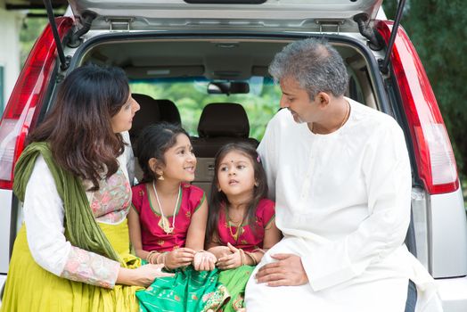 Happy Asian Indian family sitting in car talking and smiling happily, ready to summer vacation.