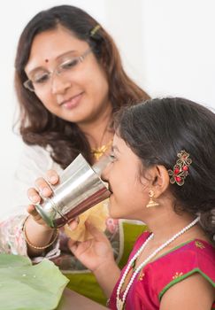 Indian family dining at home. Photo of child drinking water on dining table. Traditional home cook meal.