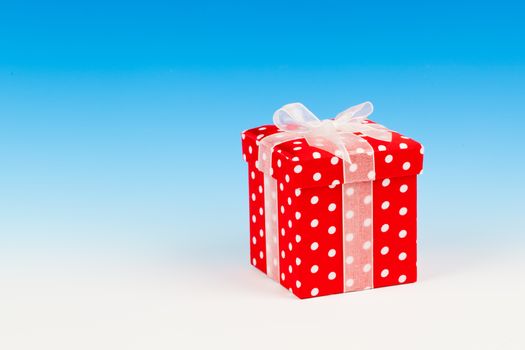 red gift box, polka dots with bow on blue background