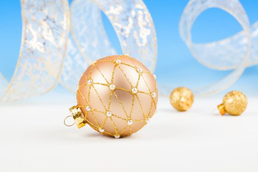 Christmas balls with ribbon on snow, on blue background