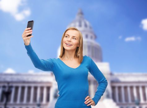 technology, travel and internet concept - smiling woman taking self picture with smartphone camera