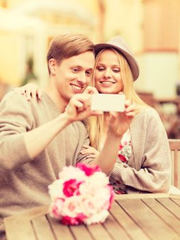 summer holidays, dating and technology concept - couple taking picture with smartphone at cafe in the city