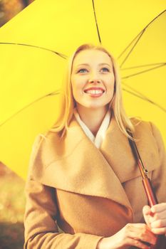 holidays, seasons, happy people concept - smiling woman with yellow umbrella in the autumn park