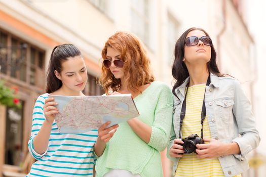 tourism, travel, leisure, holidays and friendship concept - teenage girls with map and camera outdoors