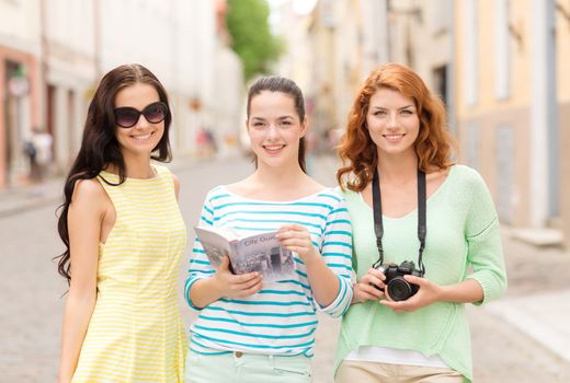 tourism, travel, leisure, holidays and friendship concept - smiling teenage girls with city guide and camera outdoors