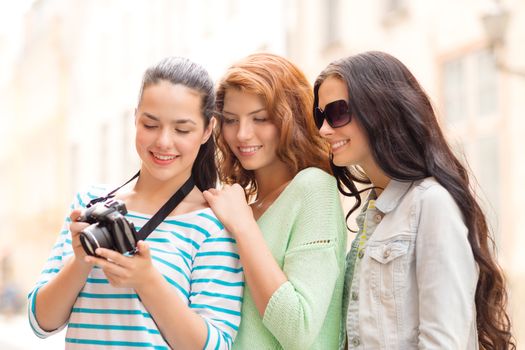 tourism, travel, leisure, holidays and friendship concept - smiling teenage girls with camera outdoors