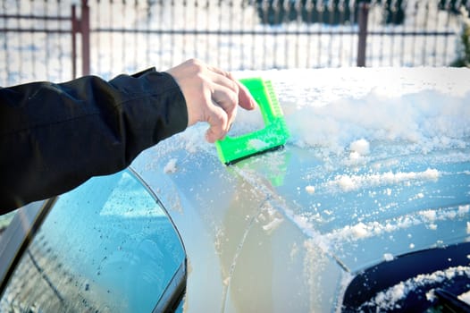 Winter and car. Person remove snow from car. Car covered with snow and ice. 