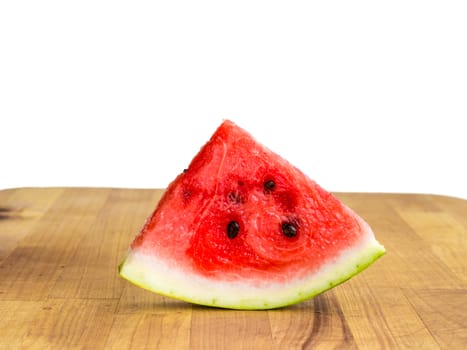 Isolated watermelon slice, cutout quarter, fresh red with seeds on wooden board