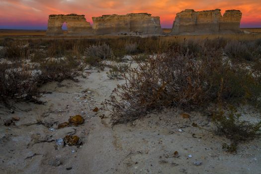 A horizontal landscape photography image of Monument Rocks in Kansas at Sunrise.  They are also known as Chalk Pyramids.  They have plenty of fossils in the rocks.