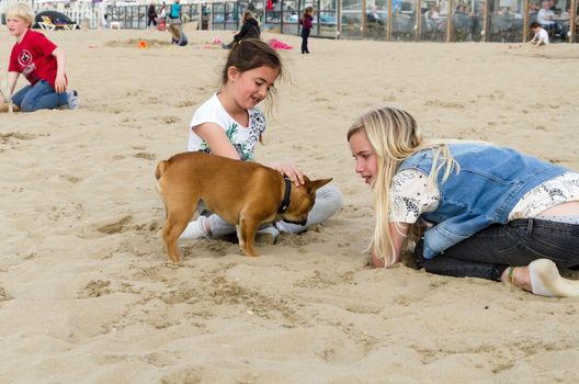 The Hague, Netherlands - May 8, 2015: Children playing at the beach, Scheveningen district in The Hague, Netherlands. Scheveningen is a modern seaside resort with a long sandy beach, an esplanade, a pier, and a lighthouse.