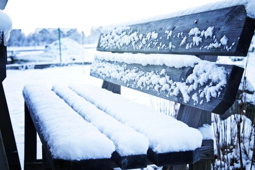 Winter and snow conceputal image. Bench covered with snow.