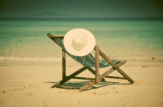 Exotic beach holiday background with white hate on beach chair