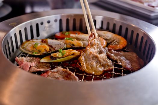 Mixed Roasted Meat and Seafood and Chopsticks on the BBQ Grill on roast.
