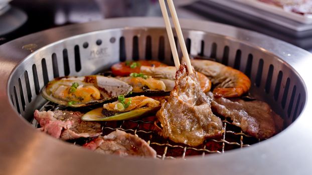 Mixed Roasted Meat and Seafood and Chopsticks on the BBQ Grill on roast.