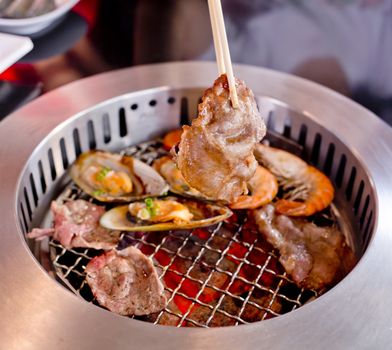 Mixed Roasted Meat and Seafood and Chopsticks on the BBQ Grill on roast.