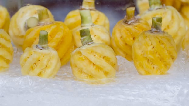 Ripe small pineapple peeled on ice at the market