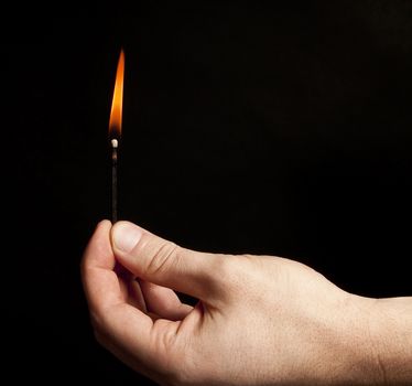 Hand holding burning match stick