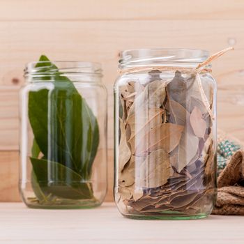 Fresh and dry bay leaves in  bowl on wooden background