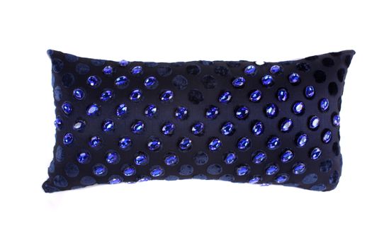A luxurious black pillow studded with blue gemstones, on white studio background.