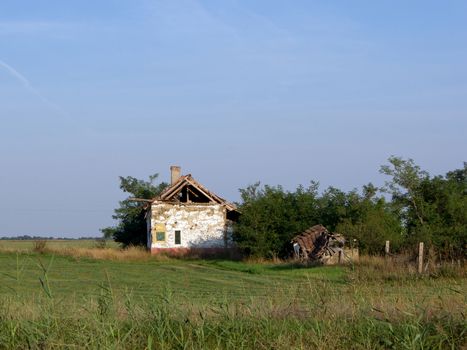 Abandoned dilapidated farmhouse on the edge of the field.