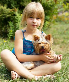 Girl 6 years old sitting on the grass with a Yorkshire Terrier