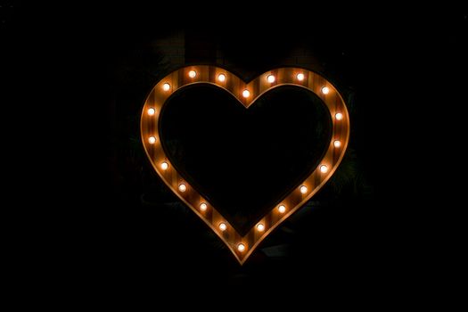 Heart sign with light bulb isolate on black background