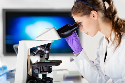 Life scientist researching in laboratory. Portrait of a attractive, young, confident female health care professional microscoping in hes working environment. Healthcare and biotechnology.