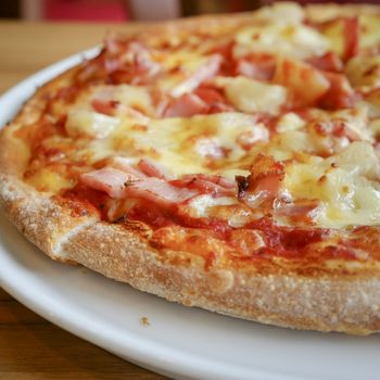 delicious hawaiian rustic style pizza made with fresh pineapples,ham and mozzarella cheese