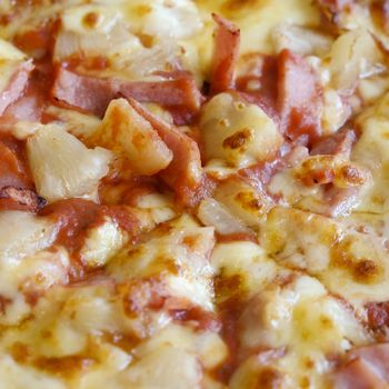 delicious hawaiian rustic style pizza made with fresh pineapples,ham and mozzarella cheese