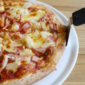 delicious hawaiian rustic style pizza made with fresh pineapples,ham and mozzarella cheese