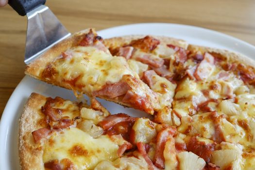 delicious hawaiian rustic style pizza made with fresh pineapples,ham and mozzarella cheese