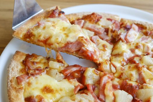 delicious hawaiian rustic style pizza made with fresh pineapples,ham and mozzarella cheese