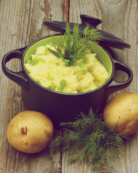 Creamy Homemade Mashed Potato with Dill and Spring Onion in Dark Blue Casserole with Lid on Rustic Wooden background. Retro Styled