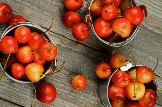 Sweet Maraschino Cherries in Three Tin Buckets closeup on Rustic Wooden background. Top View