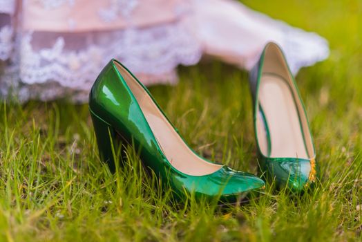 wedding emerald bridesmaid shoes on the green grass on the background of the dress
