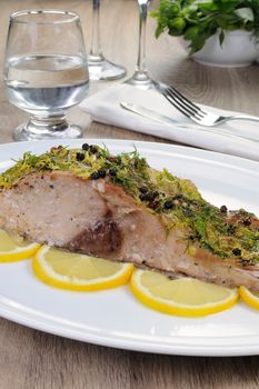 Baked piece of carp with lemon dill sauce on a plate