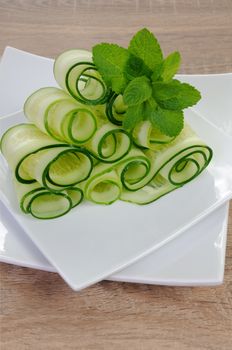 Salad cucumber ribbons twisted in rolls with mint