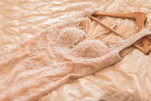 wedding dress of the bride is lying on the bed